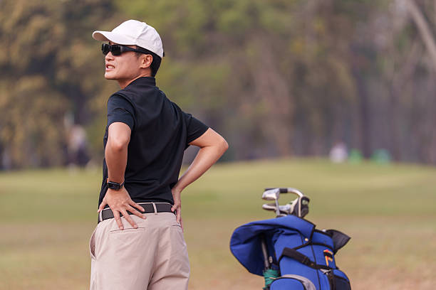 Golfer holding his lower back in pain on the golf course