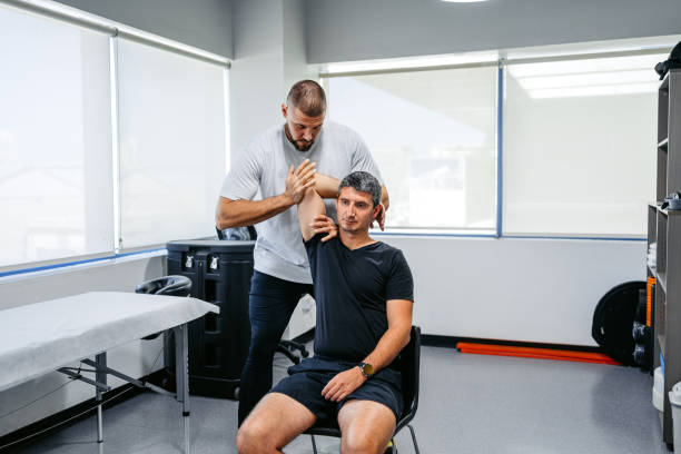 Physical therapist performing hands-on shoulder mobilization with a patient in the clinic