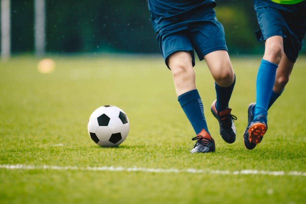 Two soccer players sprinting for the ball on a grass field